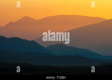 I contorni di una successione di colline e montagne al tramonto nelle Highlands scozzesi, Scotland, Regno Unito Foto Stock