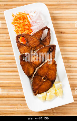 Vista superiore della veggente deliziosi/sgombro filetti di pesce fritto servito con le carote grattugiate, materie anelli di cipolla, limone. Foto Stock