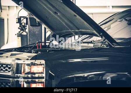 Di fronte a un morto batteria auto. Carrello con cappa aperta in Auto Service Area Come arrivare salto. Foto Stock