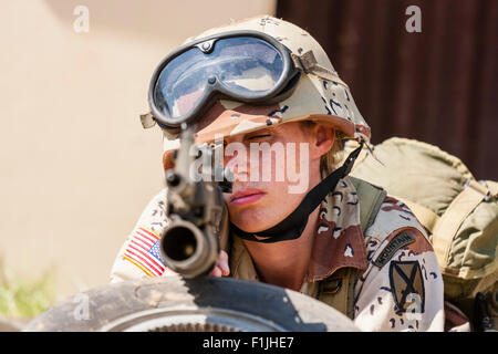 Esercito Americano, Black Hawk rievocazione, Guerra e Pace show. Soldato donna posa rivolta verso il basso, puntando la pistola direttamente al visualizzatore. Focus sul volto di donna. Foto Stock