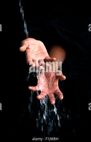 L'acqua che scorre sul nero mani. Foto Stock