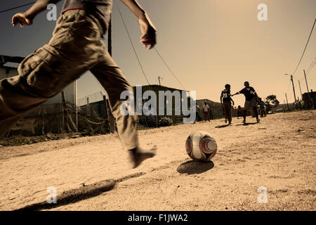 Ragazzi che giocano a calcio nelle township Foto Stock