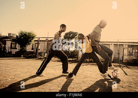 Ragazzi che giocano a calcio nelle township Foto Stock