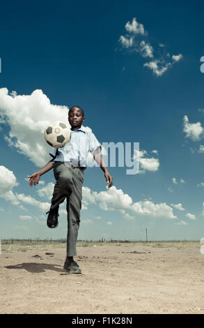 Scuola africana pupillo gioca con un pallone da calcio Foto Stock