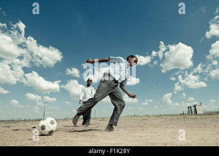 Scuola africana pupillo gioca con un pallone da calcio Foto Stock