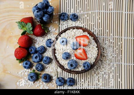 Fiocco di avena e frutti di bosco freschi nella ciotola sul bambù tabella mat sfondo con spazio per il testo. Vista dall'alto. Foto Stock