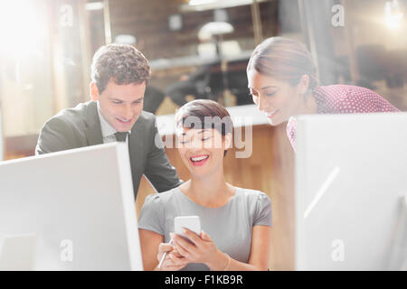 La gente di affari texting con il cellulare in ufficio Foto Stock