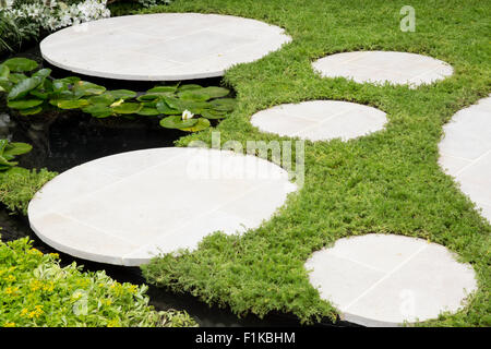 Piccolo giardino con prato in camomilla e pavimentazione rotonda pietre a gradini d'acqua caratterizzate da laghetti viventi paesaggi RHS Hampton Court Flower Show UK Foto Stock