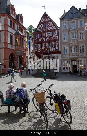 La gente seduta sulla piazza del mercato con la metà case con travi di legno e i negozi a Bernkastel-Kues Mosel Germania Foto Stock