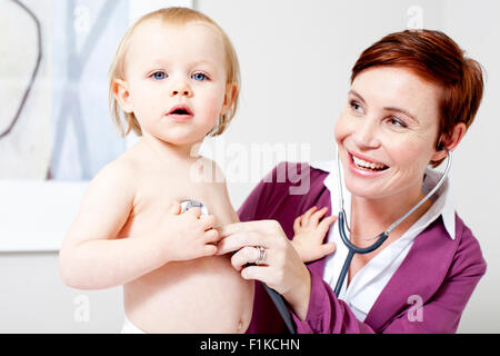 Un pediatra ascoltando un bambino di respirazione Foto Stock