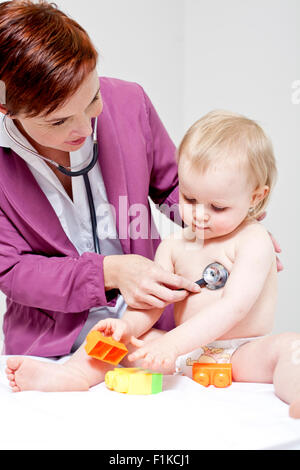 Un pediatra ascolto di un bambino la respirazione mentre ella è in corso di riproduzione Foto Stock