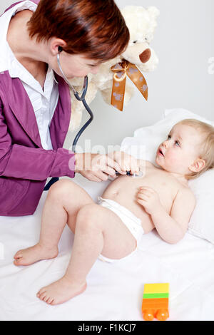 Un pediatra ascoltando un bambino di respirazione Foto Stock