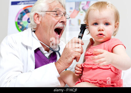 Un pediatra esaminando un bambino orecchio Foto Stock