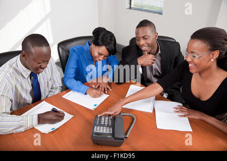 Quattro per il nero business persone sedute intorno ad un tavolo avente una riunione, sorridente Foto Stock