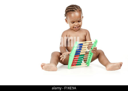 In infante seduto davanti a uno sfondo bianco, giocando con un abaco Foto Stock