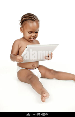Un bambino si siede di fronte a uno sfondo bianco, a giocare con un PC tablet Foto Stock