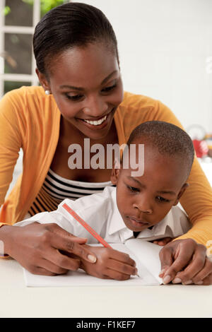 Giovane africana madre aiutare suo figlio con i suoi compiti Foto Stock