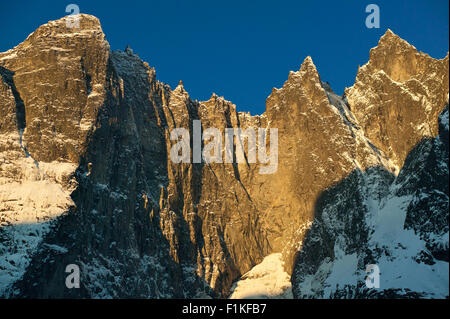 La mattina presto luce sul 3000 piedi verticale Trollveggen, o TheTroll Wall, e le cime Trolltindene nella valle Romsdalen, Møre og Romsdal, Norvegia. Foto Stock