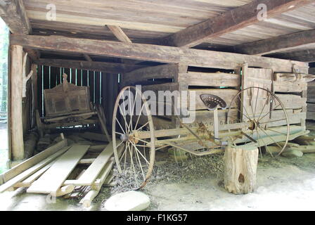 All'interno di un vecchio fienile in legno dal 1900, con un carro di legno e vintage aratro. Foto Stock