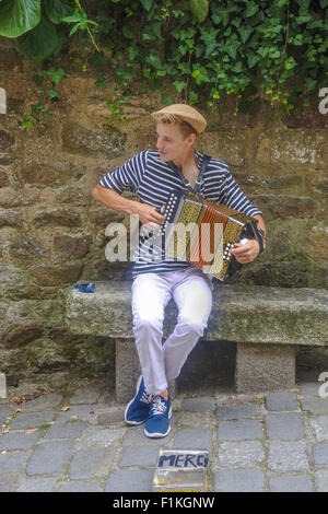 Giovane musicista di strada a suonare la sua fisarmonica sulla Rue du Petit Fort, Dinan, Brittany, Francia Foto Stock