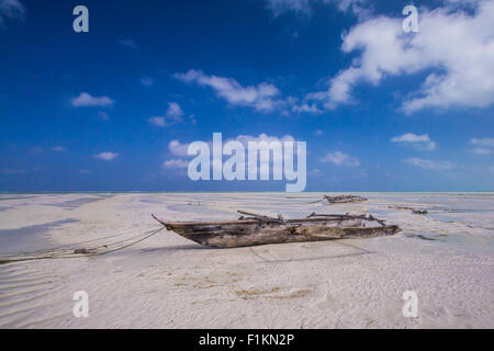 Dhow imbarcazione in legno che giace a secco a bassa marea su una spiaggia all'Oceano Indiano vicino a Zanzibar, Tanzania Foto Stock