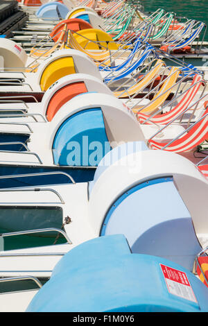 Funny fila di coloratissimi pedalò parcheggiato sul lago. Foto Stock