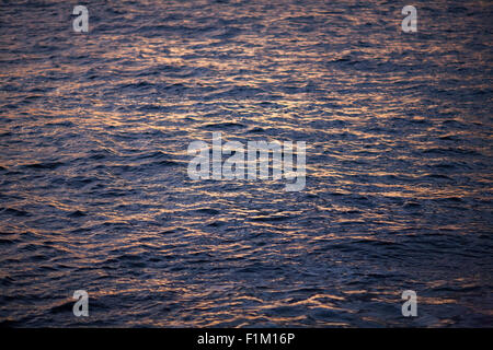 Blu scuro del mare oceano onde increspato colore rosa con riflessi gialli frame completo Foto Stock