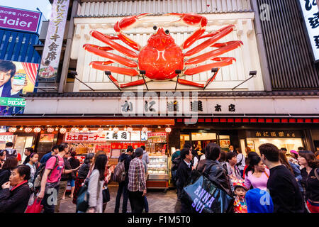 Osaka, Dotonbori. Esterno del famoso ristorante di granchio, Kani Doraku, con meccanica gigante di granchio arancione al di sopra di entrata. Strada frequentata da persone a piedi. Foto Stock