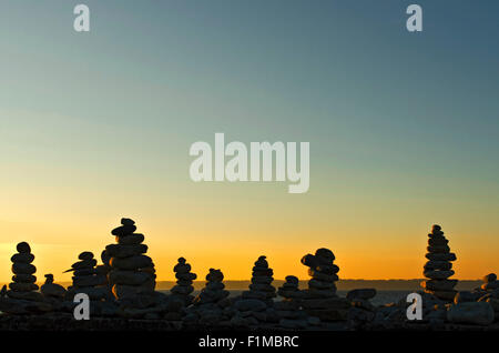 L'uomo ha fatto mucchi di pietre piatte al tramonto Foto Stock