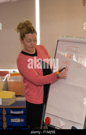 Femmina di insegnante di scuola primaria al lavoro sulla matematica in aula, Londra, Regno Unito. Foto Stock