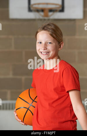 Ritratto di ragazza con basket in palestra della scuola Foto Stock