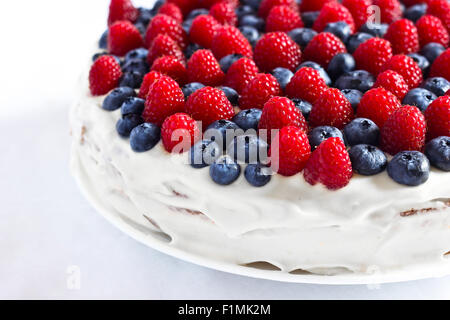 Dolce cremoso torta di cioccolato e crema di latte, guarnito con mirtilli e lamponi Foto Stock