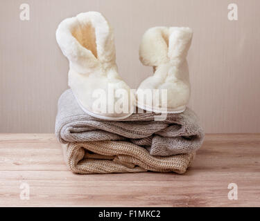 Coppia di caldo inverno pantofole di pelle di pecora (alpaca) sulla pila di calda panni di lana (messa a fuoco selettiva) Foto Stock