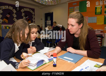 L'insegnante di scuola primaria aiutando la pupilla in classe, Londra, Regno Unito. Foto Stock