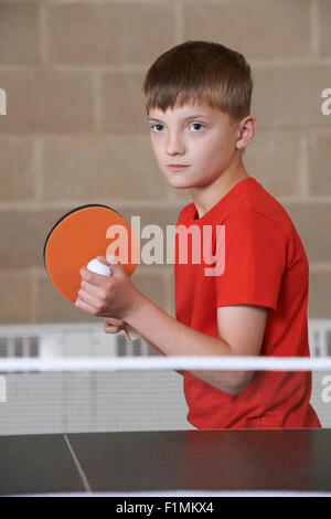 Ragazzo giocando a ping-pong nella palestra della scuola Foto Stock