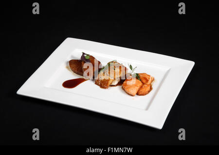 Misto di pesce grigliato in piastra bianca su sfondo nero Foto Stock