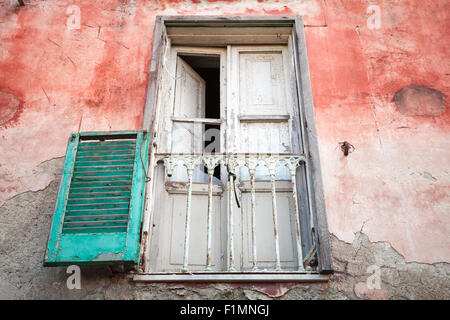 Vecchia casa abbandonata la parete bianca con balcone in legno porte e persiane verdi, Gaeta, Italia Foto Stock