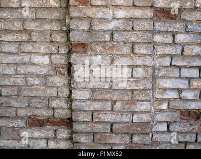 Dettaglio di un muro di un vecchio rosso mattone con rivestimento bianco sulla superficie da utilizzare come sfondo o wallpaper Foto Stock