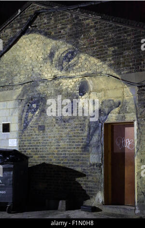 I fantasmi di faccia. Un murale di un volto di donna dipinta sul frontone di un vecchio edificio industriale in Peckham, a sud-est di Londra Foto Stock