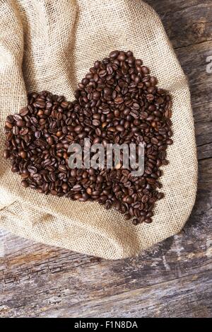 Cuore di caffè. Grande forma di cuore su tela creato da chicchi di caffè. Foto Stock