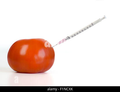 Organismo geneticamente modificato cibo Concetto di immagine. Ago della siringa iniettata all'interno di pomodoro Foto Stock