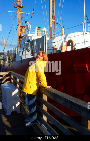 Una donna godendo di un caldo sole vicino all'Astoria museo marittimo nave. Foto Stock