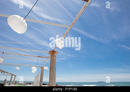 Terrazza accanto al mare con pergola, colonne e lampade di carta una giornata di vento Foto Stock