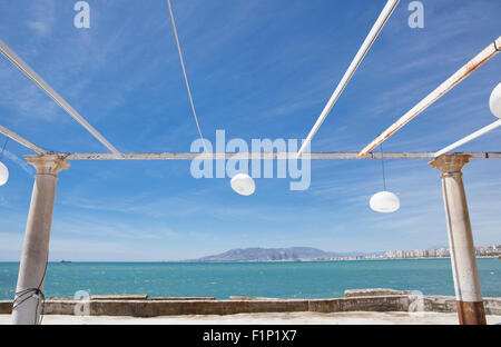 Terrazza accanto al mare con pergola, colonne e lampade di carta una giornata di vento Foto Stock