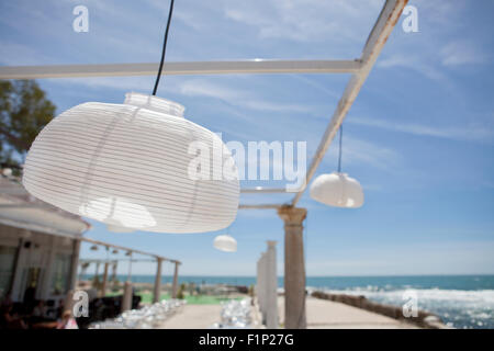 Terrazza accanto al mare con pergola, colonne e lampade di carta una giornata di vento Foto Stock