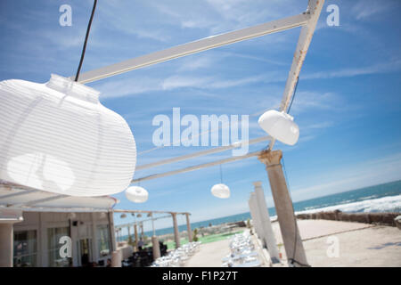 Terrazza accanto al mare con pergola, colonne e lampade di carta una giornata di vento Foto Stock