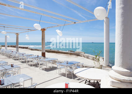 Terrazza accanto al mare con pergola, colonne e lampade di carta una giornata di vento Foto Stock