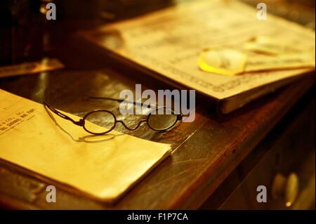 Scrivania Vintage - La vecchia scrivania di legno con libri e bicchieri. Antica collezione di foto. Foto Stock