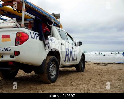 Un RNLI Van con bagnini guarda come surfers brave l'acqua in Cornwall Inghilterra REGNO UNITO Foto Stock