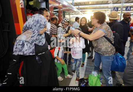Una donna tedesca mano barrette di cioccolato ai migranti dalla Siria. I migranti dalla Siria, Afghanistan e in altri paesi è arrivato su un treno da Budapest/Ungheria a Monaco di Baviera stazione ferroviaria principale Hauptbahnhof Il 31 agosto. 2015 a Monaco di Baviera, Germania. Migliaia di migranti sono in viaggio verso la Germania attraverso la Turchia e la Grecia, Montenegro, Serbia, Ungheria e Austria. Foto Stock